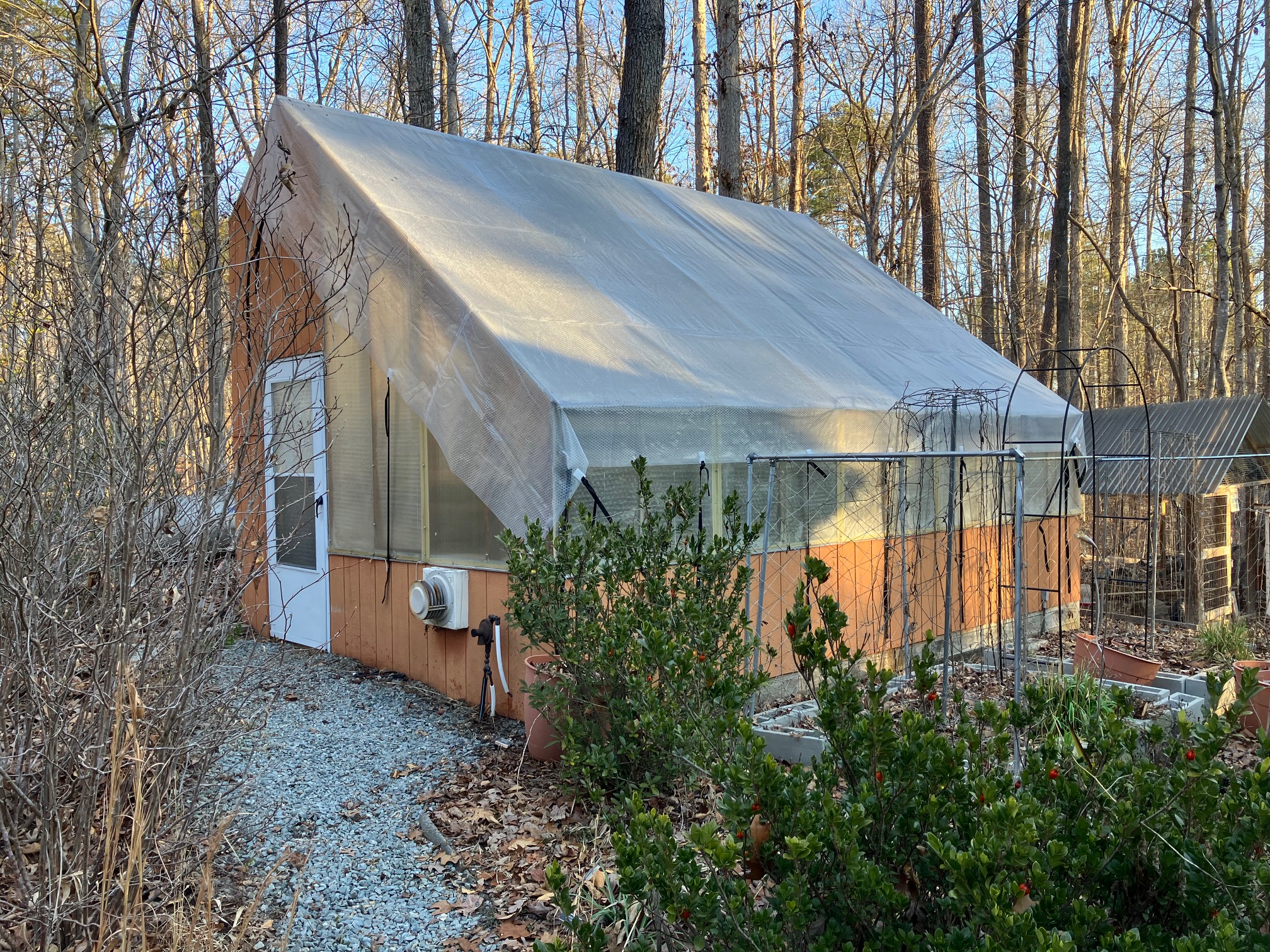 photo of a greenhouse with a solar pool cover draped over the top